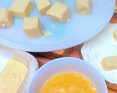 Step <p>Corte la crema fría en 24 porciones, páselas por harina (los 100 g restantes) y huevo batido y fríalas en abundante aceite caliente. Rebócelas en una mezcla de 100 g de azúcar y 1 cucharadita de canela y listo</p> illustration
